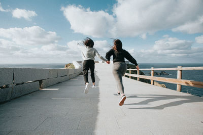 Rear view of women running against sky