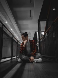 Full length of man looking at woman sitting in corridor