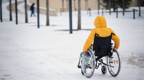 Rear view of man riding bicycle on snow