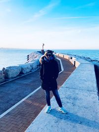 Full length portrait of woman standing by sea against sky