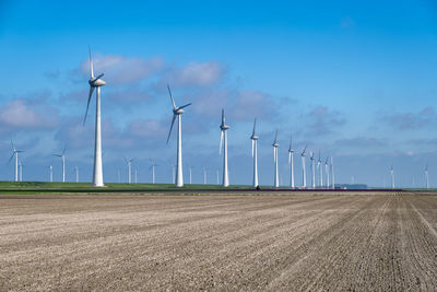 Windmills on field against sky