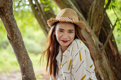 Portrait of teenage girl standing against tree trunk