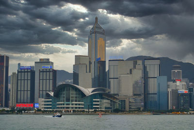 Modern buildings by river against sky in city