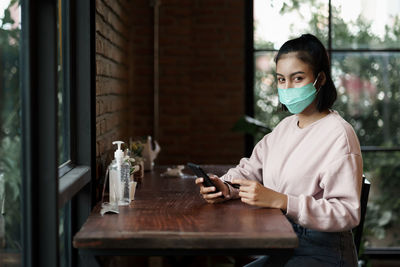 Portrait of young woman using smart phone in cafe