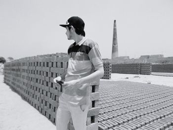 Young man standing at brick factory on sunny day