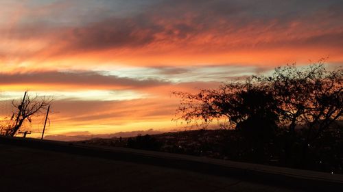 Scenic view of landscape against cloudy sky at sunset