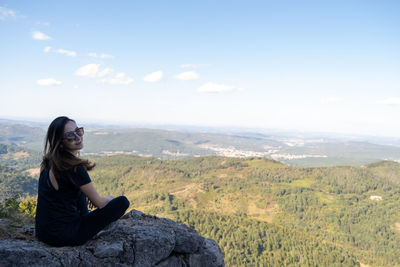Portrait of woman sitting on mountain against sky