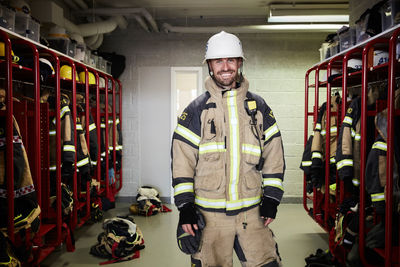 Portrait of smiling male firefighter standing in locker room at fire station