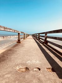 Empty footbridge against blue sky