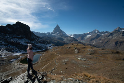 Rear view of woman standing on mountain against sky