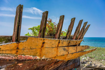 Rusty metallic structure on beach against sky