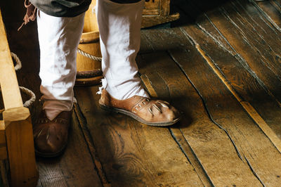 Low section of man standing on wooden floor