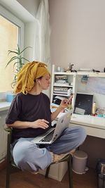 A mid-age woman wearing a yellow scarf on her head after shower working at her home office