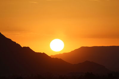 Scenic view of silhouette mountains against romantic sky at sunset