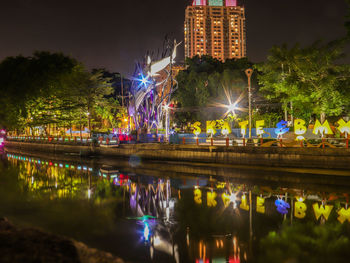 Illuminated buildings by lake at night