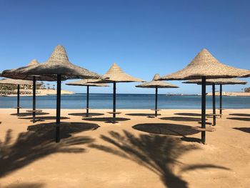 Thatched umbrella at beach against clear sky