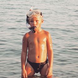 Full length of shirtless boy looking at sea