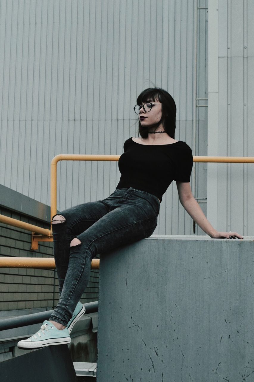 sitting, casual clothing, wall - building feature, full length, steps, staircase, young adult, person, looking at camera, day, attitude