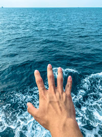 Close-up of hand against sea