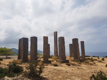 Wooden structure on field against cloudy sky