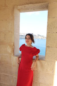 Portrait of young woman standing against wall