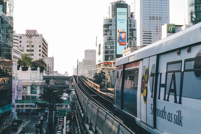 Railroad tracks amidst buildings in city against sky