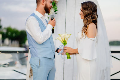 Midsection of man holding woman standing by flowers