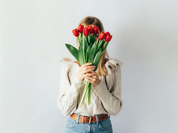 Woman holding red tulip against white background