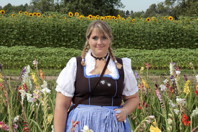 Portrait of overweight young woman standing amidst plants on field