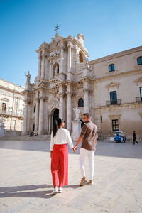 People standing by historical building against sky