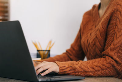 Midsection of woman using laptop at home