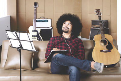 Smiling young man playing guitar in studio