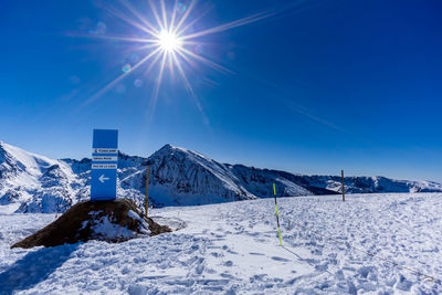Scenic view of snow covered mountains against blue sky on sunny day