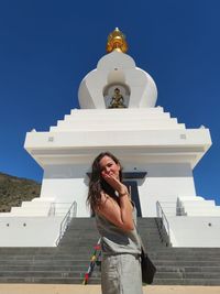 Young woman standing outside temple against building