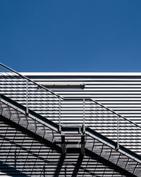 Low angle view of staircase against building against clear blue sky