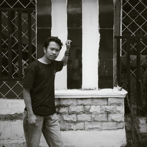 Portrait of young man standing against wall