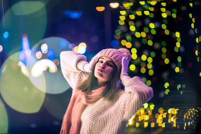 Young woman wearing hat standing at night