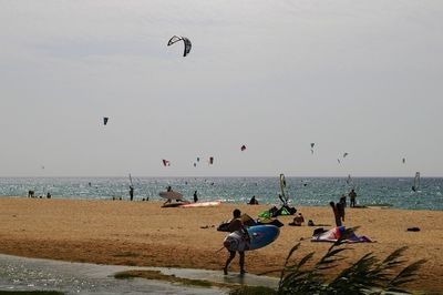 People enjoying at beach against clear sky