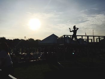 Silhouette man on woman against sky during sunset