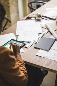 High angle view of female designer using digital tablet while sitting by desk at home office