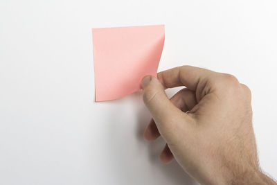 Close-up of hand holding paper against white background