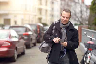 Portrait of man using smart phone on city street