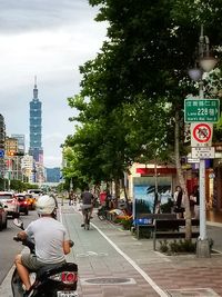 People on city street against cloudy sky