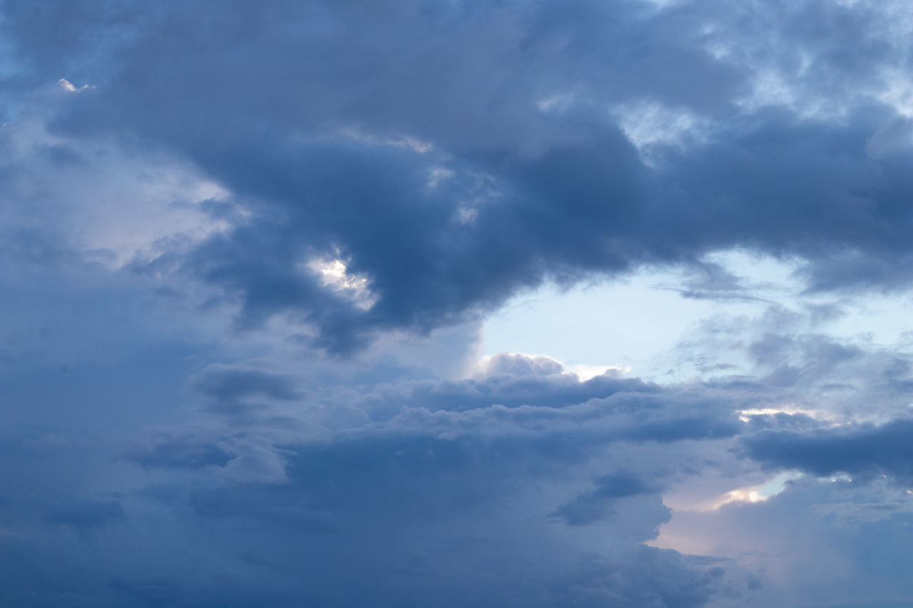 LOW ANGLE VIEW OF SUN STREAMING THROUGH CLOUDS IN SKY