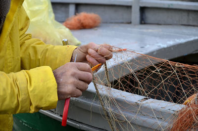 Midsection of man holding fishing net and scissors