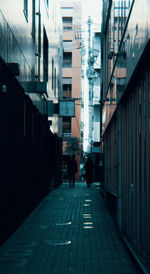 People walking on footpath amidst buildings in city