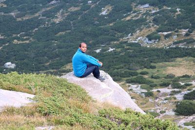 Man sitting on rock against mountains