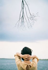 Rear view of woman at sea against sky