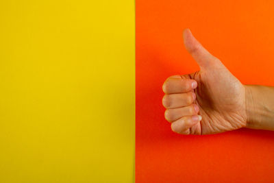 Close-up of human hand against yellow wall