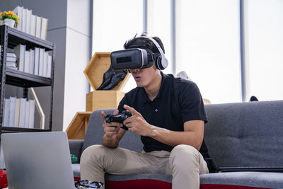 Man playing video game wearing virtual simulator while sitting at home